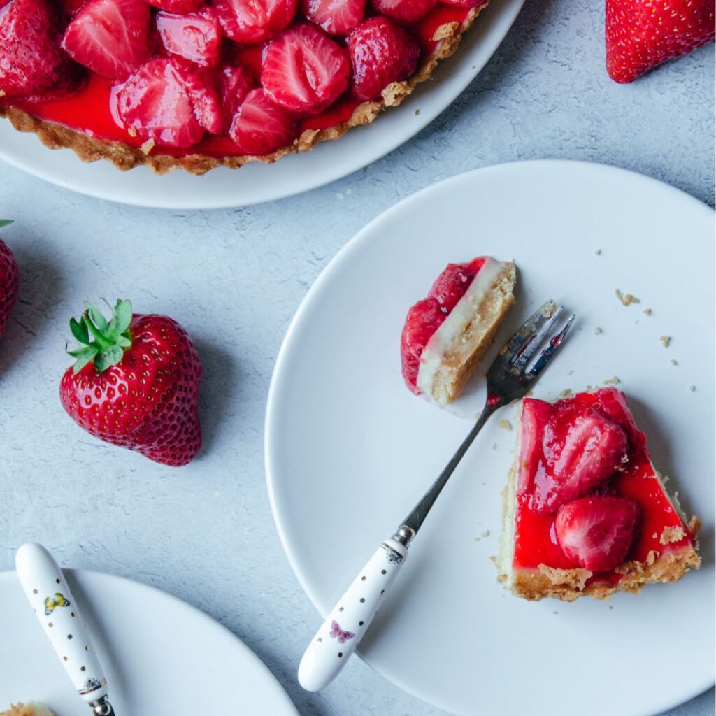tarte aux fraises coupées das une assiette blanche avec une fourchette et une fraise à côté
